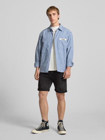 Männermodel trägt Jeansshorts mit Umschlag Modell 'RICK' von Jack & Jones, schwarze Farbe, Baumwoll-Mix, Regular Fit, Ganzkörperansicht von vorne.