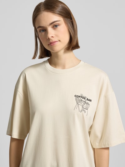Frauenmodel trägt Oversized T-Shirt mit Statement-Print von REVIEW aus reiner Baumwolle, Oversized-Fit, Rundhalsausschnitt, Nahaufnahme Oberkörper.