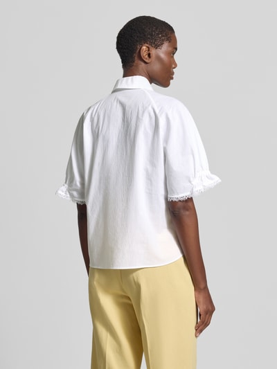 Frauenmodel trägt eine weiße Bluse mit 1/2-Arm und Hemdblusenkragen von Luisa Cerano, reine Baumwolle, Fransensaum, Rückansicht.