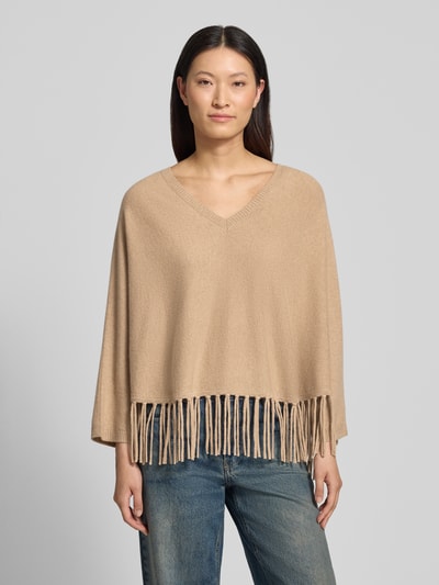 Frauenmodel trägt Relaxed Fit Pullover aus Woll-Mix mit Kaschmir-Anteil von HERZENS in Beige, Strick-Optik, Fransen-Abschluss, V-Ausschnitt, langärmelig, Ganzkörperansicht von vorne.
