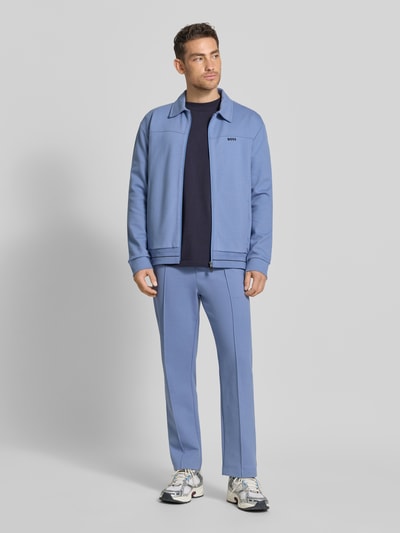 Männermodel trägt Regular Fit Sweatpants aus Baumwoll-Mix Modell 'JT_Member Hurley' von BOSS Green in Hellblau, Unifarbe, Label Stitching, fixierte Bügelfalten, elastischer Bund, seitliche Eingrifftaschen, Sweat-Material, Ganzkörperansicht von vorne.