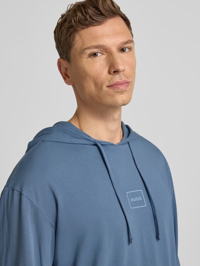 Mannelijk model draagt Regular Fit Hoodie uit katoenmix model 'LAZE' van HUGO in effen blauw met labelprint, zweetstof. Nahaufnahme bovenlichaam.