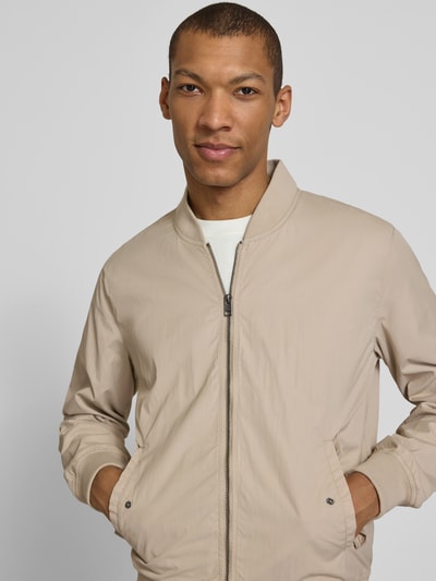 Mężczyznamodel nosi Regular Fit Bomberjacke mit Stehkragen od s.Oliver RED LABEL, jednolity kolor, zamek błyskawiczny, boczne kieszenie z patką, kieszeń wewnętrzna, prążkowane wykończenia, krój regular fit, stójka, długi rękaw, ganzkörperansicht z przodu.