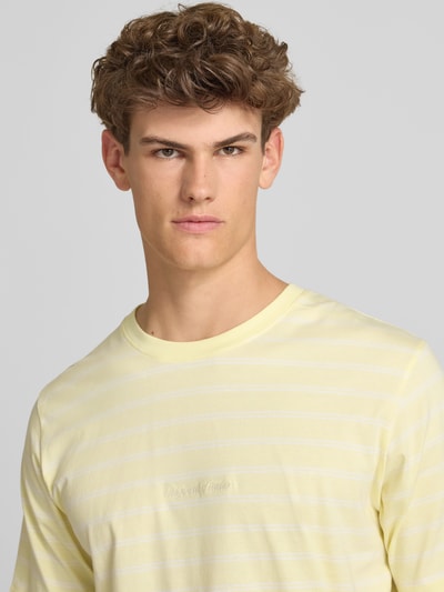 Männermodel trägt T-Shirt mit Streifenmuster und Label-Stitching von Jack & Jones in Gelb, reine Baumwolle, Nahaufnahme Oberkörper.