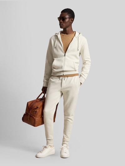 Męski model nosi Regular Fit Sweatjacke aus Baumwoll-Mix von Polo Ralph Lauren w kolorze kremowym, gładka tekstura, całopostaciowy widok z przodu.