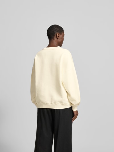 Frauenmodel trägt Oversized Sweatshirt mit Logo-Print von Anine Bing aus Reine Baumwolle in Creme mit elastischen Abschlüssen und Rundhalsausschnitt, Oversized-Fit, Rückenlänge bei Größe S 61 cm, Ganzkörperansicht Rückansicht.