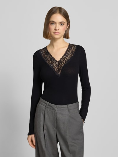Vrouwenmodel draagt zwart shirt met lange mouwen van viscosemix met stretch, effen design, met kant, V-hals, model 'SIRI' van PIECES, nauwsluitend model, ruglengte maat S 49 cm, Nahaufnahme Oberkörper.