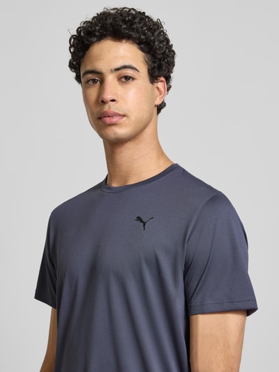 Männermodel trägt Regular Fit T-Shirt mit Logo-Print Modell 'Solid' von PUMA PERFORMANCE in Dunkelgrau, Rundhalsausschnitt, Nahaufnahme Oberkörper. Herren T-Shirt, Rückenlänge bei Größe M: 70 cm.