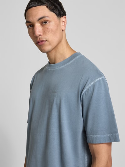 Männermodel trägt Regular Fit T-Shirt aus reiner Baumwolle von Closed in Blau mit Rundhalsausschnitt und Label-Print, Nahaufnahme Oberkörper.