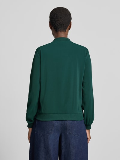 Frauenmodel trägt Regular Fit Blouson mit Reißverschluss-Detail von VERO MODA in Dunkelgrün, glatte Oberfläche, Damen Bomberjacke, Ganzkörperansicht Rückansicht.