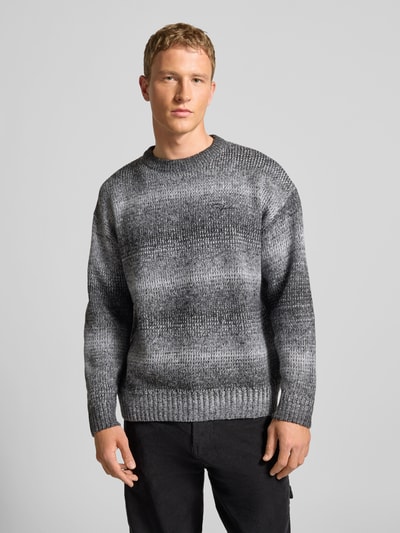Męski model nosi Oversized Strickpullover mit gerippten Abschlüssen od Pegador, melanżowe szarości, dzianina, okrągły dekolt, całkowity przód.