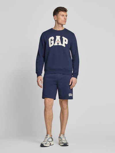 Männermodel trägt Sweatshirt mit Logo und Rundhalsausschnitt von GAP in Dunkelblau aus Baumwoll-Mix, Regular-Fit, Ganzkörperansicht von vorne.