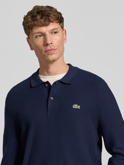 Männermodel trägt Regular Fit Poloshirt aus reiner Baumwolle von Lacoste in Dunkelblau, strukturierte Oberfläche, Nahaufnahme Oberkörper. Herren Poloshirt von Lacoste.