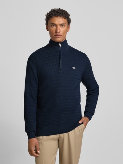 Männermodel trägt Strickpullover mit Stehkragen von Gant in Dunkelblau, Reine Baumwolle, Regular-Fit, Gerippte-Abschlüsse, kurzer Reißverschluss, Label-Stitching, Ganzkörperansicht von vorne.
