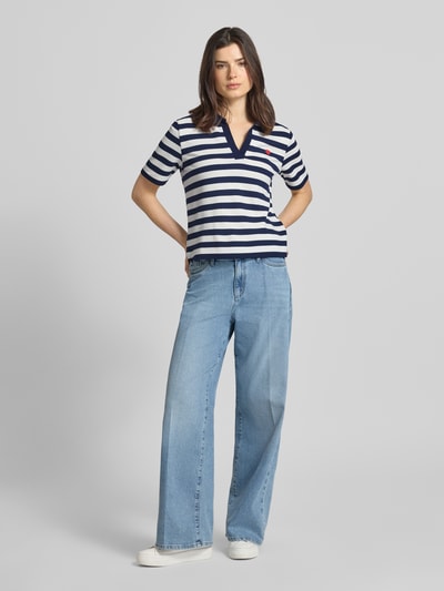 Frauenmodel trägt Regular Fit Poloshirt mit Viskose-Anteil Modell 'Februar' von More & More, elastischer blau-weiß gestreifter Stoff, Motiv-Stitching, Kurzarm, Polokragen, lässige Form, Ganzkörperansicht von vorne.