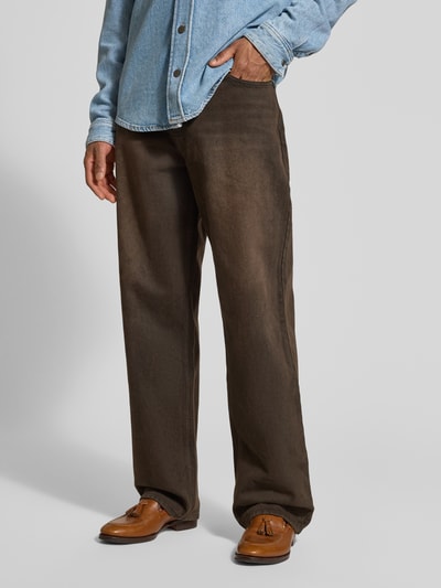 Männermodel trägt Relaxed Fit Jeans mit Knopf- und Reißverschluss von KARL KANI in Braun, 5-Pocket-Design, Ganzkörperansicht von vorne.