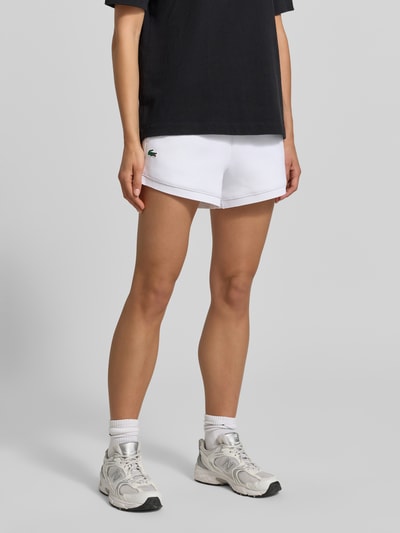 Frauenmodel trägt Regular Fit Sweatshorts mit Logo-Applikation von Lacoste Sport, Optik: Unifarben, Materialverarbeitung: Sweat, seitliche Eingrifftaschen, elastischer Bundabschluss, Ganzkörperansicht von vorne.