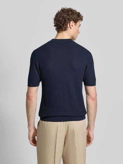Männermodel trägt Slim Fit poloshirt met viscose van Roy Robson in tricotlook met structuurpatroon, elastische boorden, ruglengte maat M 67 cm, mouwlengte maat M 27 cm, katoen- en viscosemix, polokraag, met korte mouwen, beige broek, kleuren donkerblauw en beige, geheel beeld, rugaanzicht.