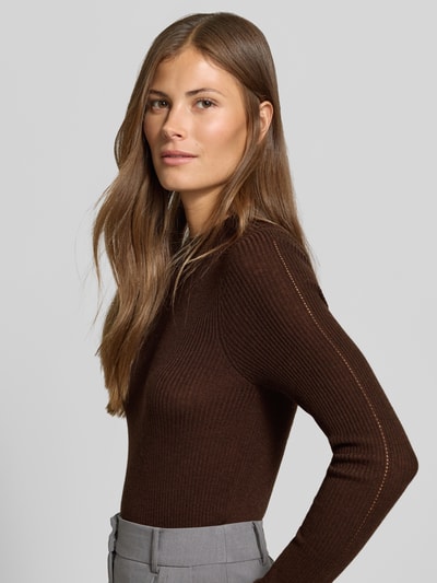 Frauenmodel trägt Strickpullover mit Woll-Anteil von MYON, Ripp-Optik, Lochmuster vorn, eng anliegend, Nahaufnahme Oberkörper.