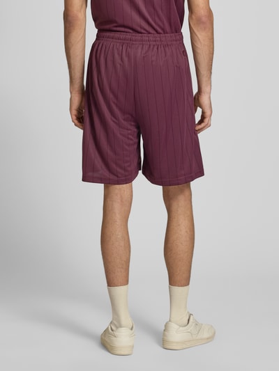 Männermodel trägt Shorts mit elastischem Bund Modell 'Insignia Shadow' von KARL KANI, Herren, Relaxed-Fit, Streifenmuster, Ganzkörperansicht Rückansicht.