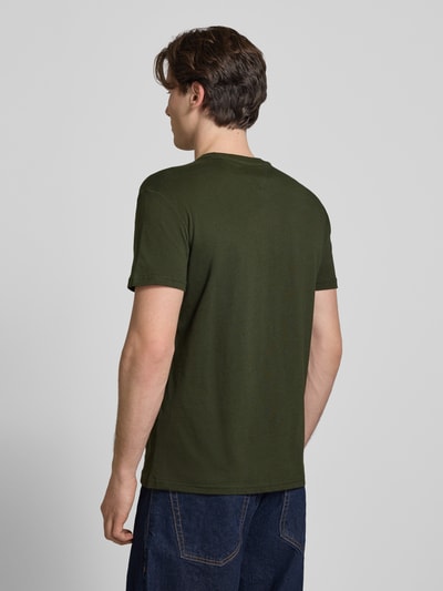 Männermodel trägt Regular Fit T-Shirt aus reiner Baumwolle von Tommy Jeans in Uni-Olivgrün, Jersey-Material, Ganzkörperansicht Rückansicht.