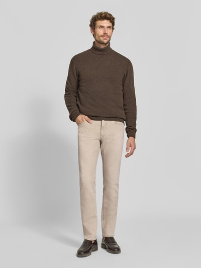 Männermodel trägt Slim Fit Jeans aus Baumwoll-Mix Modell 'Chuck' von Brax in Beige, glatte Struktur, Herren Slim Fit Jeans, Ganzkörperansicht von vorne.