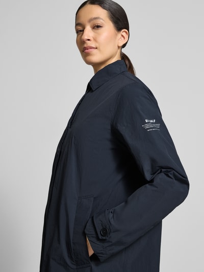 Vrouwenmodel draagt Jacke mit Umlegekragen Modell 'VERNE' van ECOALF in donkerblauw met losse fit, knoopsluiting, steekzakken, labelprint. Nahaufnahme bovenlichaam.