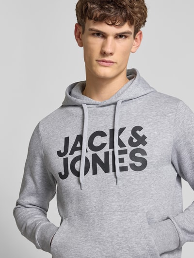 Męski model nosi Hoodie mit Label-Print und Känguru-Tasche od Jack & Jones, szary, bawełniany, regular fit, zbliżenie na górę ciała.