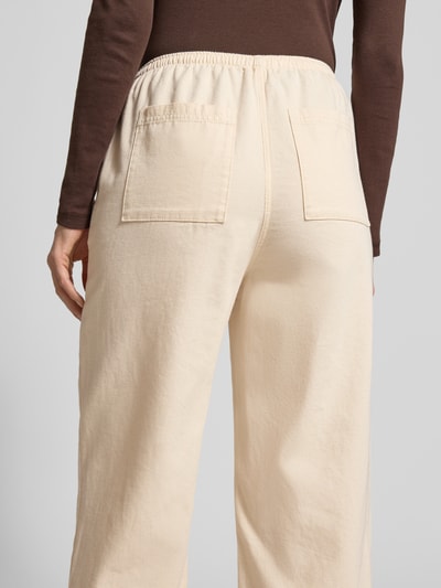 Frauenmodel trägt Wide Fit Stoffhose mit elastischem Bund Modell 'Lycaz' von American Vintage in Beige, reine Baumwolle, Ganzkörperansicht Rückansicht.