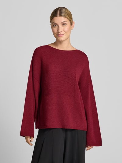 Frauenmodel trägt Oversized Pullover aus reiner Baumwolle in Strick-Optik von Emporio Armani in Dunkelrot mit elastischen Abschlüssen, Ganzkörperansicht von vorne.