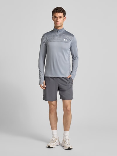 Männermodel trägt Sweatshirt mit Stehkragen von Under Armour in Grau mit kurzem Reißverschluss, Slim-Fit und Label-Print, Ganzkörperansicht von vorne. Rückenlänge bei Größe L: 73 cm, Ärmellänge 72 cm.