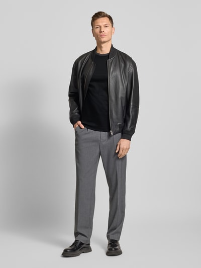 Männermodel draagt Slim Fit T-Shirt aus reiner Baumwolle Modell 'TESSLER 202' van BOSS, zwart, unicolor, label-detail, vooraanzicht, Ganzkörperansicht von vorne.