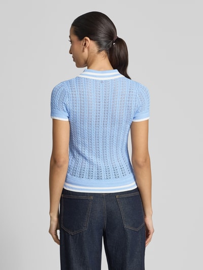 Modelka nosi Strickshirt aus Viskose-Mix mit Polokragen von Guess, krój slim fit, mieszanka wiskozy, paski w kontrastowym kolorze, długość tyłu w rozmiarze S: 51 cm, długość rękawów w rozmiarze S: 13 cm, widok całej sylwetki od tyłu.
