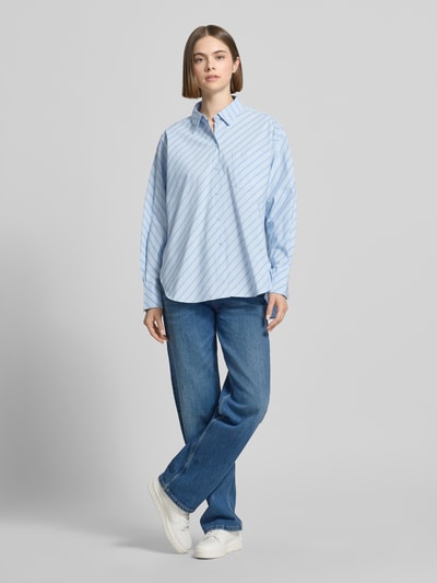 Frauenmodel trägt Relaxed Fit Bluse mit Brusttasche von JJXX aus Reine Baumwolle, hellblau mit weißen Streifen, Ganzkörperansicht von vorne. Modell 'JAMIE' mit Hemdblusenkragen, Rückenlänge bei Größe S 78 cm, Ärmellänge 60 cm.