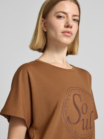 Frauenmodel trägt Damen T-Shirt mit Statement-Print Modell 'BANU' von Soyaconcept in Braun, Material-Mix mit Micromodal-Anteil, Relaxed-Fit, Rundhalsausschnitt, Nahaufnahme Oberkörper.
