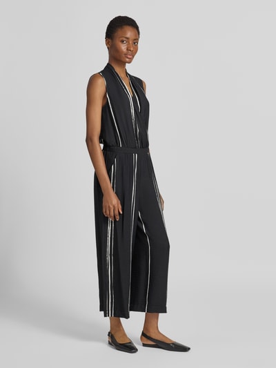 Vrouwenmodel draagt Jumpsuit aus Viskose-Mix im Allover-Look Modell 'Cafalli' van someday in zwart met witte strepen, regular fit, wikkel-look, volledig beeld van voren, ruglengte 139 cm, borstwijdte 50 cm, totale lengte 136 cm, binnenbeenlengte 63 cm.