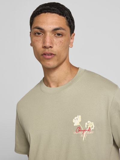 Mannelijk model draagt T-shirt met motiefprint en ronde hals van Jack & Jones, puur katoen, regular fit, ruglengte maat M 70 cm, nahaufnahme bovenlichaam.