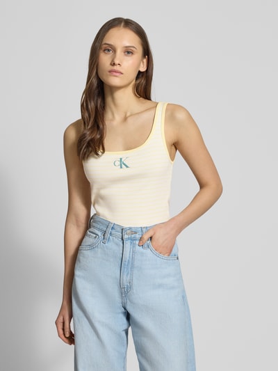 Frauenmodel trägt Trägertop in Ripp-Optik mit Logo von Calvin Klein Jeans in Creme mit Logo, Slim Fit, Nahaufnahme Oberkörper.