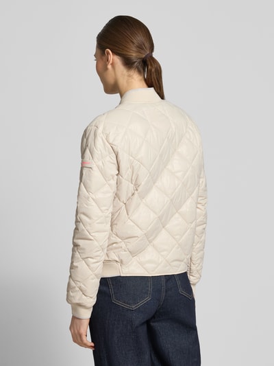 Frauenmodel trägt Steppjacke mit Zweiwege-Reißverschluss Modell 'BOY' von Frieda & Freddies in Beige mit Rautensteppung, Ganzkörperansicht Rückansicht. Regular Fit, Stehkragen, Reißverschlusstaschen, Maße Größe 36.