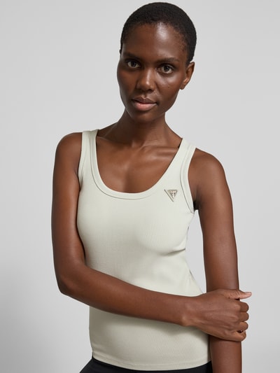 Frauenmodel trägt Slim Fit Top aus Viskose-Mix Modell 'Colette' von Guess Activewear, heller Ton, gerippte Struktur, Nahaufnahme Oberkörper.