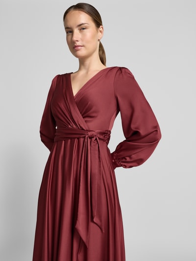 Frauenmodel trägt bordeauxrotes Tailliertes Abendkleid mit Bindegürtel von Jake*s Cocktail, weicher Stoff, Nahaufnahme Oberkörper.