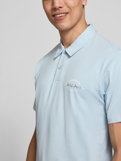 Männermodel trägt Poloshirt mit Label-Print Modell 'BRANDON' von Jack & Jones in Hellblau, Reine Baumwolle, Regular-Fit, Nahaufnahme Oberkörper.