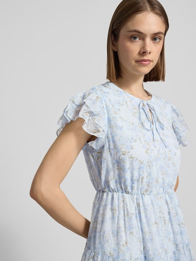 Frauenmodel trägt Tailliertes Freizeitkleid mit Volants Modell 'ELIZA' von Only mit Florales-Allover-Muster, Mini-Länge, Rundhals, Materialverarbeitung Crinkle, in hellblauen und cremefarbenen Tönen, Nahaufnahme Oberkörper.