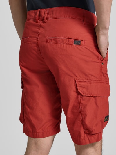 Mannenmodel draagt rode Bermudas met Cargozakken van camel active van puur katoen, regular fit, steekzakken, labeldetail, binnenbeenlengte maat 32: 26 cm, bandwijdte maat 32: 44 cm. Ganzkörperansicht Rückansicht.