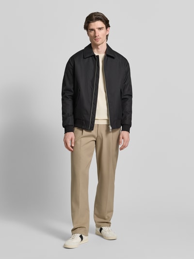 Männermodel trägt Jacke mit Reißverschluss von MCNEAL in Schwarz mit Kentkragen, Pattentaschen, Regular-Fit, gerippte Abschlüsse, Ganzkörperansicht von vorne. Rückenlänge 68 cm, Schulterbreite 48 cm, Brustweite 57 cm, Ärmellänge 65 cm, Größe M.