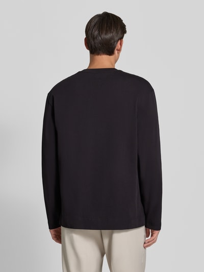 Männermodel trägt Regular Fit Longsleeve aus reiner Baumwolle Modell 'Ryan' von Wood Wood in Schwarz, glatte Textur, Ganzkörperansicht Rückansicht. Herren Longsleeve, Logo-Stitching, Rückenlänge bei Größe M: 79 cm.