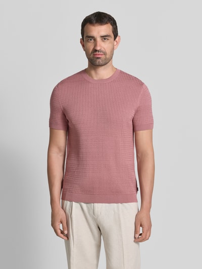 Männermodel trägt Strickshirt mit Strukturmuster Modell 'Elio' von JOOP! COLLECTION in Rosa, reine Baumwolle, Slim Fit, Rundhalsausschnitt, Ganzkörperansicht von vorne.
