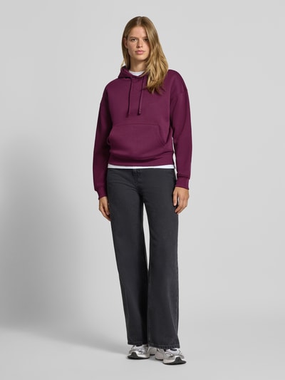 Frauenmodel trägt Regular Fit Hoodie aus Baumwoll-Mix Modell 'BEST' von ONLY in Dunkellila, kombiniert mit dunkler Jeans, Damen Hoodie von ONLY, Ganzkörperansicht von vorne.