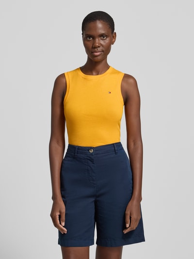 Frauenmodel trägt Slim Fit Tank Top aus reiner Baumwolle Modell 'SLIM CODY' von Tommy Hilfiger in Gelb, Optik: Unifarben, Logo-Stitching, Rundhals, breite Träger, Ganzkörperansicht von vorne.
