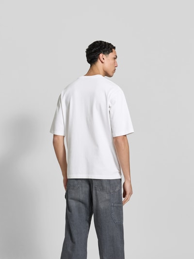 Männermodel trägt Loose Fit T-Shirt aus reiner Baumwolle von Dsquared2 in Weiß, Kurzarm, Jeans kombiniert, Ganzkörperansicht Rückansicht.